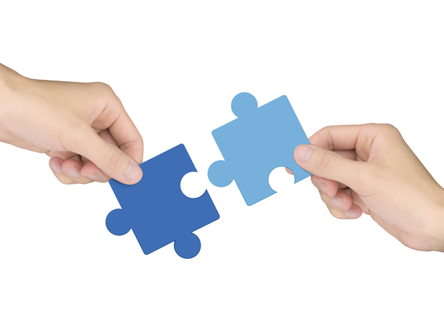 cooperation concept: hands holding jigsaw pieces